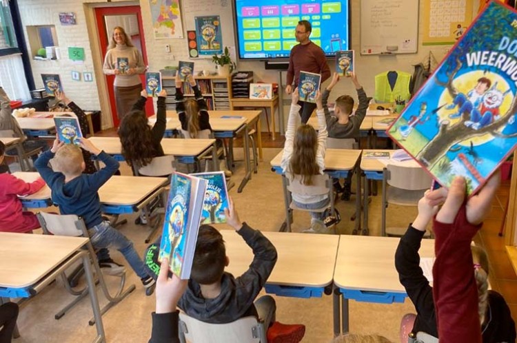 Wethouder Sørensen deelt boeken uit en leest voor op school